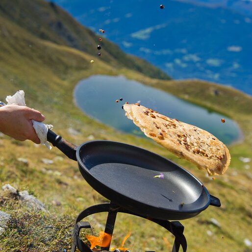 Kaiserschmarrn wird in einer Pfanne in die Luft geworfen, oberhalb des Grünbachsees | © TV Kiens_Franz Gerdl