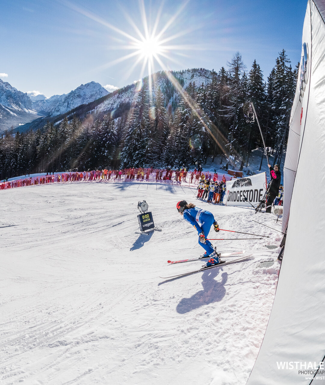 Eine Skirennläuferin beim Start auf der Erta Piste mit Aussicht auf die Dolomiten bei strahlendem Sonnenschein. | © Harald Wisthaler
