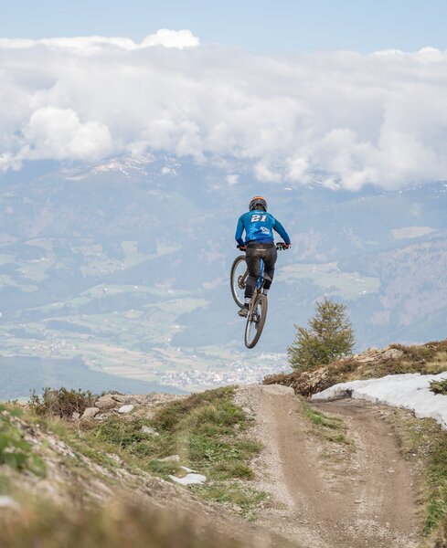 Biker springt mit seinem Bike über die Downhillstrecke. | © Gianvito Coco